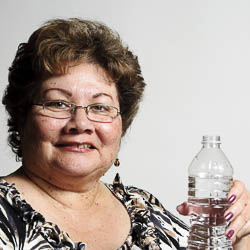 a mature woman holding a bottle of water ready to drink it.